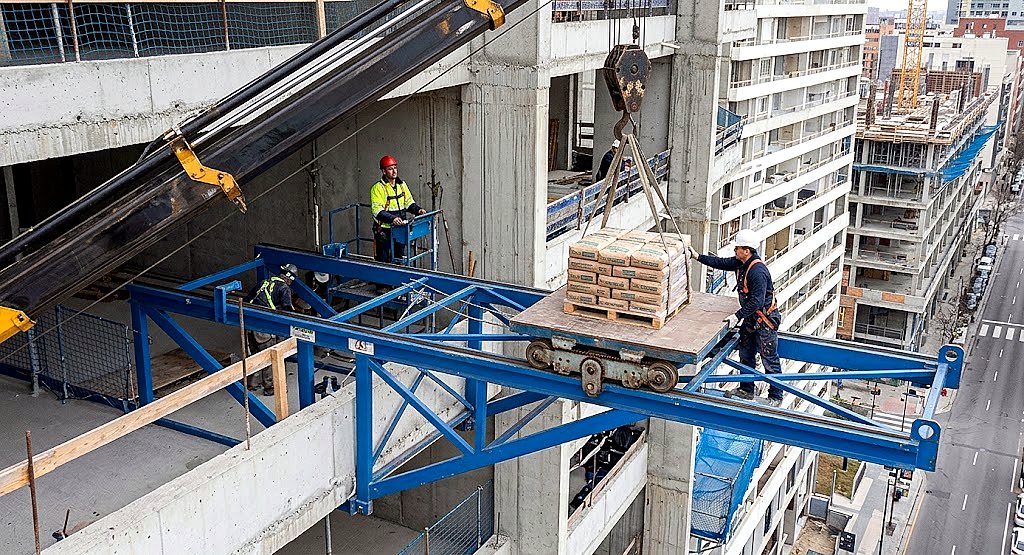 Plataforma en uso recibiendo materiales desde pluma grúa